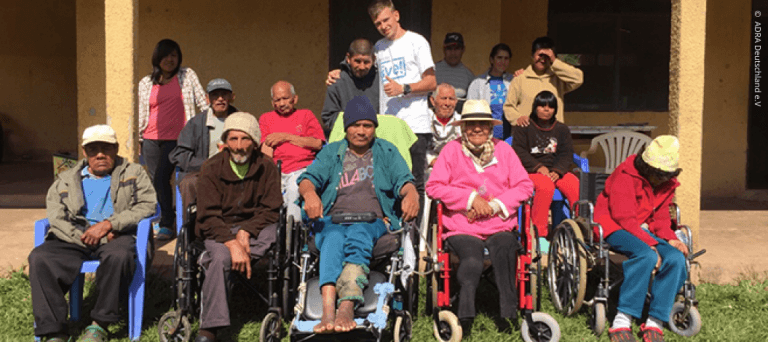 Florian steht in der Mitte einer Gruppe von Menschen mit körperlichen Beeinträchtigungen in Bolivien.