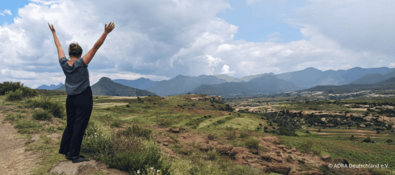 Katharina Donhauser ein Jahr mit ADRAlive! in Lesotho: Sie steht mit erhobenen Armen vor einer wunderschönen Landschaft