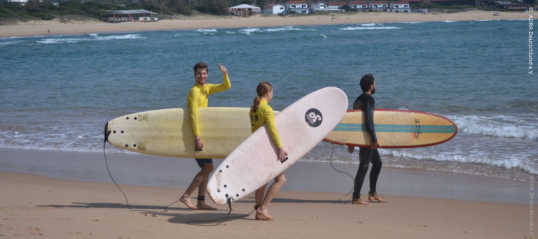 Freiwillige von ADRAlive! laufen mit Surfbrettern am Strand in Mosambik