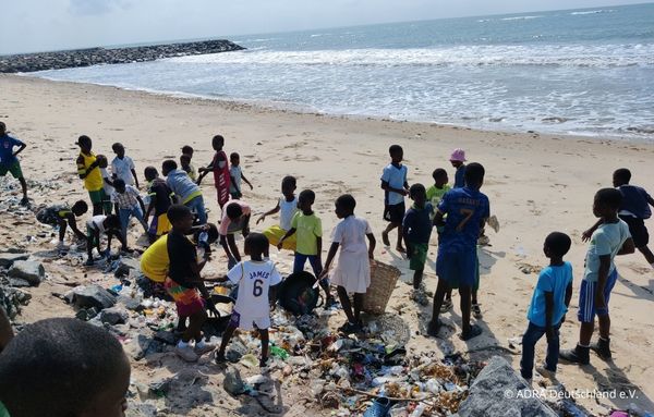 Viele Kinder sammeln Plastikmüll und Abfälle am Strand, direkt am Meer. Gemeinsam tragen sie zur Säuberung des Strandes bei.