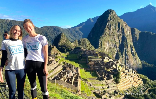 Zwei ADRAlive-Freiwillige tragen ADRA-T-Shirts und posieren vor der Ruinenstätte Machu Picchu in Peru.