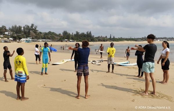 Freiwilligenarbeit in Mosambik: Gruppe von Jugendlichen und Volunteers beim Surftraining am Strand in Ponta do Ouro