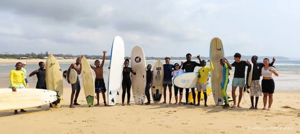 Freiwilligenarbeit bei LWANDI-Surf in Mosambik: Gruppe von Jugendlichen und Freiwilligen mit Surfboards am Strand von Ponta do Ouro
