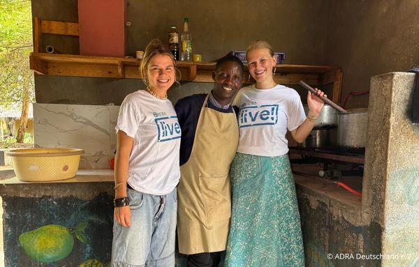 Zwei Freiwillige und ein Mitarbeiter stehen gemeinsam in der Küche von The Baobab Home in Bagamoyo