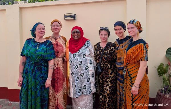 Sechs Frauen in farbenfroher Kleidung stehen gemeinsam für ein Gruppenfoto in Arusha