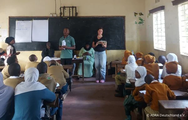 Mitarbeitende und eine Freiwillige von CWCD bei einem Workshop mit Schülerinnen und Schülern in einem Klassenraum in Arusha