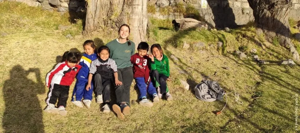 ADRA-Freiwillige sitzt mit fünf Kindern der Kindertagesstätte Nuestro Hogar im Freien in Arequipa, Peru