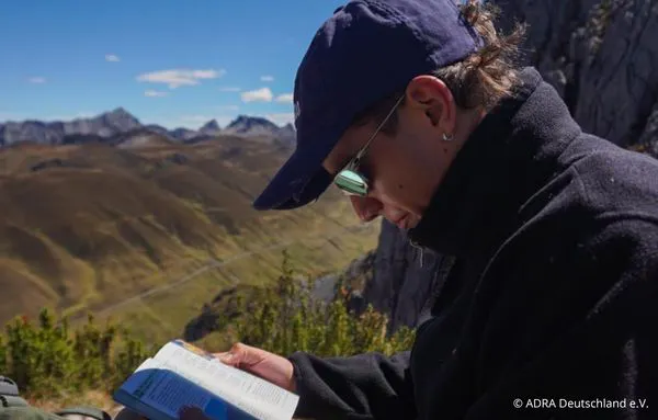 Ein Freiwilliger liest ein Buch in der Berglandschaft der peruanischen Anden