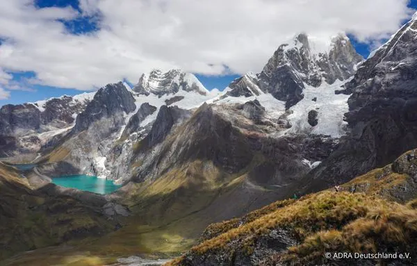 Türkisfarbener Bergsee zwischen schneebedeckten Gipfeln und Gletschern in den peruanischen Anden